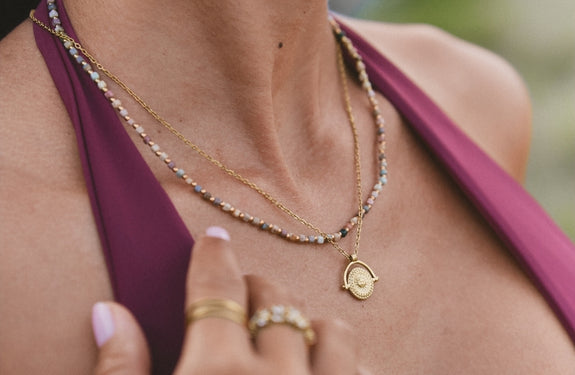Lulu Midnight Beaded Stone Necklace, worn on a neck with a cream top, layered gold chains