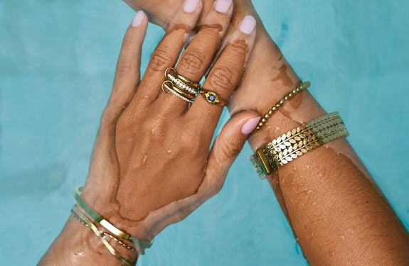 18K Gold Crystal Vine Ring, worn on a finger with a cream knit sleeve, gold leaf-and-vine setting